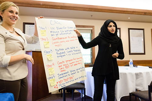 Two women present their work to a group of people.